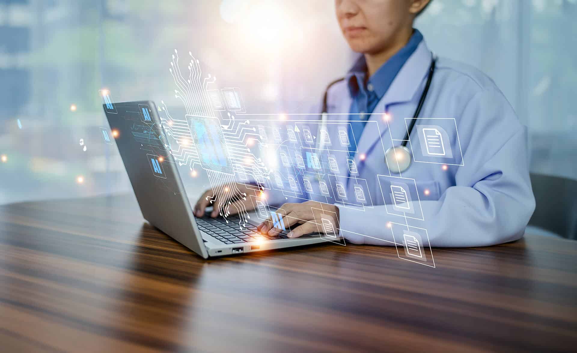 Physician at desktop typing on a laptop with data flow diagram overlaying the screen